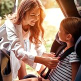 women putting seatbelt on child