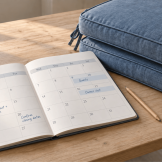 October rental calendar with guest stays, owner visits, cleaning and closing notes beside stacked blue outdoor seat cushions.