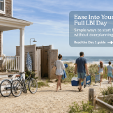Family walking from an LBI vacation rental to the beach on their first full LBI day with bikes, beach gear, dunes, and ocean views.